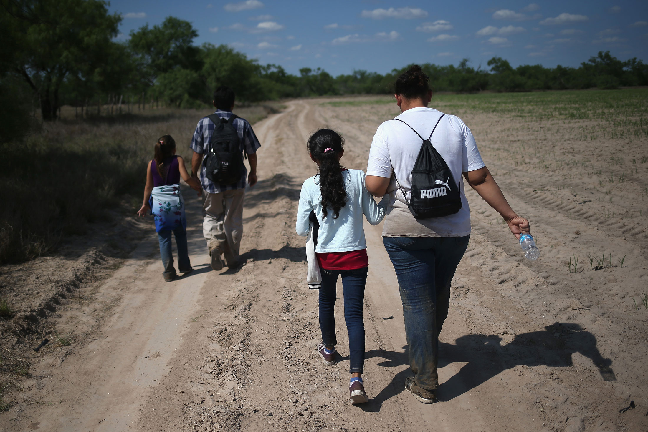 ROMA, TX - APRIL 14:  Central American immigrant families walk through the countryside after crossing from Mexico into the United States to seek asylum on April 14, 2016 in Roma, Texas. Border security and immigration, both legal and otherwise, continue to be contentious national issues in the 2016 Presidential campaign.  (Photo by John Moore/Getty Images)